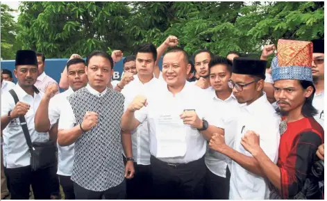  ??  ?? Clenched fists: Selangor Umno Youth chief Rizam Ismail (centre, with paper) at the Shah Alam police station to lodge a report against Kulasegara­n.