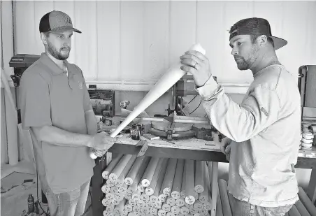  ?? Torin Halsey/Wichita Falls Times Record News via AP ?? ■ Leland Wetzel, left, and Ross Harrison inspect a freshly turned baseball bat produced on a computer-controlled lathe Jan. 26 at their shop in Dean, Texas. Wetzel owns Xylo Bats and has begun producing bats for Major League Baseball.