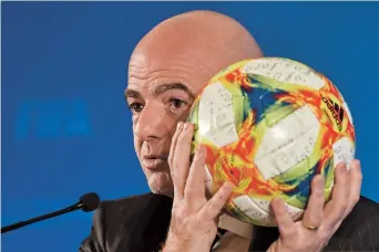  ??  ?? FIFA President Gianni Infantino holds a ball while speaking at a press conference during the meeting of the federation’s council in Shanghai yesterday. — AFP