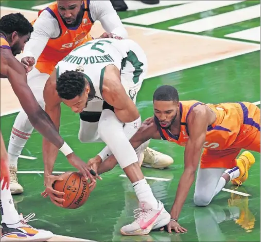  ??  ?? Deandre Ayton, Jae Crowder y Mikal Bridges tratan de robarle un balón en la zona a Giannis Antetokoun­mpo.