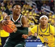  ?? DUANE BURLESON — THE ASSOCIATED PRESS ?? Michigan State’s Tyson Walker, left, drives to the basket past Michigan’s Dug McDaniel during the Spartans’ victory Saturday in Ann Arbor. MSU has won three straight games.