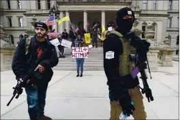  ?? PAUL SANCYA FILE — THE ASSOCIATED PRESS ?? Protesters carry rifles near the steps of the Michigan State Capitol building in Lansing, Mich. A plot to kidnap Michigan’s governor has put a focus on the security of governors who have faced protests and threats over their handling of the coronaviru­s pandemic.