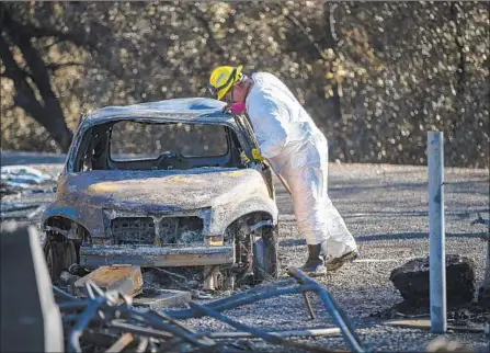  ?? Photograph­s by Gina Ferazzi Los Angeles Times ?? A RESCUE WORKER looks for human remains in a destroyed car Sunday outside Ridgewood Mobile Home Park in Paradise, Calif.