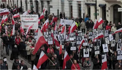  ?? (Reuters) ?? PEOPLE MARCH in Warsaw last year with portraits of 96 victims who died when a Polish government plane crashed in Smolensk, Russia, in 2010. The Banner reads: ‘Andrzej Duda our president.’