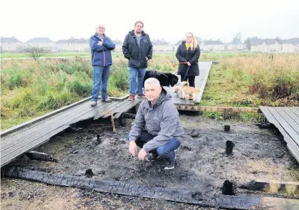  ??  ?? Double trouble George McCutcheon, front, shows September’s fire damage to the Stanrigg Park boardwalk – it has now been vandalised a further twice in four days