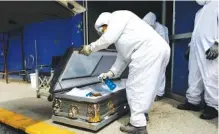  ?? AP PHOTO/REBECCA BLACKWELL ?? A worker sprays disinfecta­nt solution inside the coffin of a person suspected of dying from COVID-19 as the body arrives at the crematoriu­m at Xilotepec Cemetery in Xochimilco, Mexico City, on Monday.