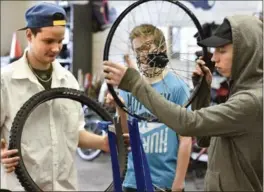  ??  ?? Marshall Cook, 15, mounts a front wheel rim in a holder as Kaleb Heibcker, 16, holds the tire in their bicycle shop class at Delta Secondary.