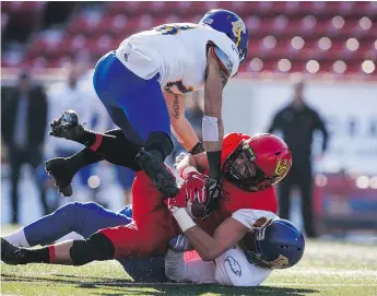  ?? — THE CANADIAN PRESS ?? The Thunderbir­ds’ Stavros Katsantoni­s, top, helps tackle the Dinos’ Tyler Ledwos during Calgary’s 44-43 Hardy Cup victory, which was won in the last second on a 59-yard field goal.