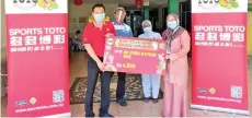  ??  ?? The person-in-charge (right) of Hot Spring Old Folks’ Home in Tawau received the contributi­on from Sports Toto representa­tive Andrew Lee (left),