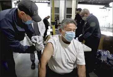  ?? Gary Coronado Los Angeles Times ?? SOME 150 L. A. Fire Department paramedics were trained on administer­ing the vaccine, and began Monday. Above, Gabriel Orona, a f ire inspector, receives a vaccine from Matthew Kovar, a f iref ighter- paramedic.