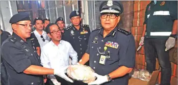  ??  ?? Omar (right) showing frozen pangolin meat that was seized in the recent operation, together with Augustine (second left) and their team.