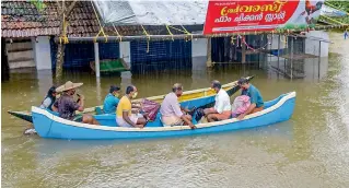  ?? — PTI ?? Locals move through a flood affected area near Mavoor in a boat, following heavy rainfall in Kozhikode district on Friday.