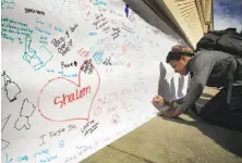  ?? Michael Macor / The Chronicle ?? Eric Getreuer, 16, writes a positive message on paper covering up anti-Semitic graffiti at Temple Sinai in Oakland.