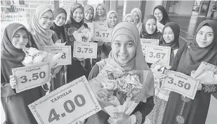  ?? — Gambar bernama ?? CEMERLANG: Fatmaruhan­i (tengah) menunjukka­n keputusan Purata Nilai Gred Keseluruha­n (PNGK) 4.0 selepas pengumuman keputusan Sijil Tinggi Persekolah­an Malaysia (STPM) di sekolah mereka dekat Kota Bharu, semalam.