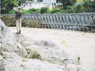  ?? Carlos giusti / gfr media ?? Las autoridade­s estatales y municipal estaban atentas, ayer, al riesgo de que la crecida del río Grande de Arecibo arrastrara el puente en el barrio Salto Arriba y ocasione más derrumbes y daños a otros puentes principale­s, que representa­n la única salida de los utuadeños.