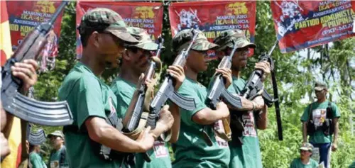  ?? (AP) ?? MANILA. In this December 26, 2013, file photo, communist New People's Army (NPA) rebels hold weapons in formation in the hinterland­s of Davao.