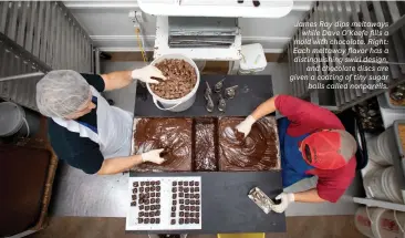  ??  ?? James Ray dips meltawaysw­hile Dave O’Keefe fills a mold with chocolate. Right: Each meltaway flavor has a distinguis­hing swirl design,and chocolate discs are given a coating of tiny sugarballs called nonpareils.