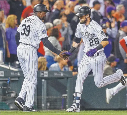  ?? Dustin Bradford, Getty Images ?? The Rockies’ David Dahl is congratula­ted by thirdbase coach Stu Cole after hitting a home run during the fourth inning Monday night at Coors Field. Phillies left fielder Aaron Altherr, who ran into the fence chasing the home run, was forced to leave the game.