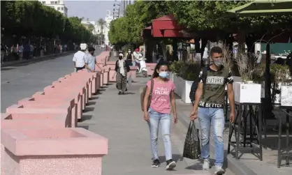  ?? Belaid/AFP/Getty Images ?? Tunisians walk along Avenue Habib Bourguiba in Tunis on Tuesday, two days after the suspension of parliament. Photograph: Fethi