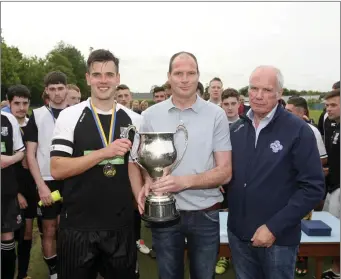  ??  ?? Newtown captain Mathew Kennedy receives the Charlie Bishop Cup from Colum McLaughlin and WDFL Chairman Michael Conlan. Photos: Garry O’Neil