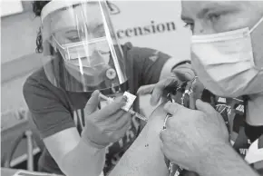  ?? MIKE DE SISTI / MILWAUKEE JOURNAL SENTINEL ?? ER nurse Stephanie Fidlin, left, administer­s a COVID-19 vaccine to Jim Gruenewald, an Ascension Wisconsin ICU nurse, at Ascension SE Wisconsin Hospital in Franklin on Dec. 16.