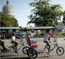  ?? Yamil Lage/AFP ?? Bicitáxi com bandeira dos EUA passa por praça de Havana