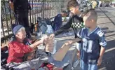  ?? NICK OZA/THE REPUBLIC ?? Jayse James, 11, and his brother Rees James, 8, give dog treats to Anne Marie for her service dog, Rules, outside the Thanksgivi­ng meal organized by St. Vincent de Paul.