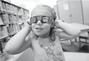  ??  ?? Emmalyn Johnson, 3, tries on her free pair of eclipse glasses at Mauney Memorial Library in Kings Mountain, North Carolina. Glasses were being given away at the library ahead of the big event on Monday.