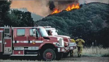  ?? Marcus Yam Los Angeles Times ?? FIREFIGHTE­RS monitor the progressio­n of the River fire on Wednesday. Low humidity, heat and wind challenged crews, although containmen­t increased on the southern Mendocino County blaze and another nearby.