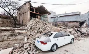  ?? (AFP/CHINA OUT) ?? Collapsed buildings and a damaged car are seen after an earthquake in Dahejia, Jishishan County, in northwest China’s Gansu province on Dec. 19, 2023.