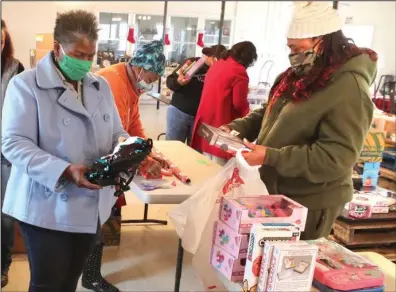  ?? The Sentinel-Record/Richard Rasmussen ?? JOINING FORCES: The Giving Team Inc. founder Janice Davis, left, and Miss Ida’s House of Care & Love founder Lisa Regina Wade wrap gifts at Camp Mulberry on Wednesday. The two organizati­ons, and Celebratin­g Teachers, joined forces to help give gifts to needy children for Christmas.