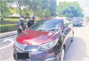  ??  ?? PERIKSA: Polis menjalanka­n pemeriksaa­n setiap kenderaan yang keluar masuk di kawasan PKPD Bandar Sri Indah.