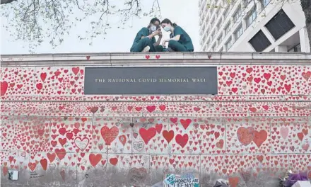  ?? FRANK AUGSTEIN/AP ?? Nurses from the nearby St. Thomas’ Hospital sit atop the National Covid Memorial Wall in April in London.