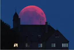  ?? Harald Tittel/dpa via AP ?? ■ The moon turns red Friday during a total lunar eclipse in Bernkastel-Kues, Germany. Skywatcher­s around much of the world enjoyed a complete lunar eclipse that was the longest this century.