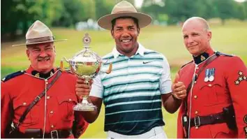  ?? AP ?? Venezuela’s Jhonattan Vegas holds up the trophy between two Mounties in Oakville, Ontario. He finished with a 12-under par total of 276 to claim the Canadian Open.