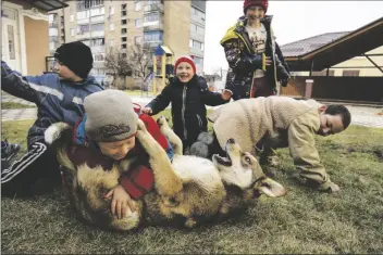  ?? RODRIGO ABD/AP ?? Children play with a dog in Bucha, on the outskirts of Kyiv, Ukraine, on April 8.