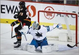  ?? PHOTOS BY JEFF MCINTOSH — THE CANADIAN PRESS ?? Sharks goalie Kaapo Kahkonen, right, shoves Flames forward Tyler Toffoli away from the net as he tries to deflect a shot during the second period on Saturday in Calgary, Alberta.