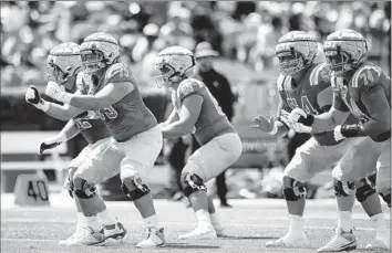  ?? Meg Oliphant For The Times ?? BRUNO FINA (75) and other UCLA linemen run drills during the team’s annual spring game. A crowd of 11,703 watched at the Rose Bowl, dwarfing previous turnouts for the showcase at Drake Stadium on campus.