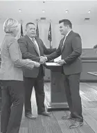  ?? ?? Ian White, a former Columbus Division of Police officer, shakes the hand of Gahanna Division of Police Chief Jeff Spence on Nov. 15 after taking an oath of office administer­ed by Mayor Laurie Jadwin, left.