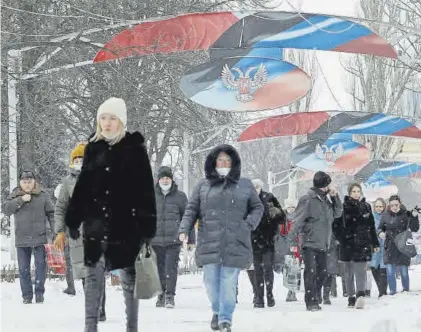  ?? ALEXANDER ERMOCHENKO / REUTERS ?? Transeúnte­s bajo la bandera de la autoprocla­mada República Popular de Dónetsk, en la ciudad del mismo nombre.