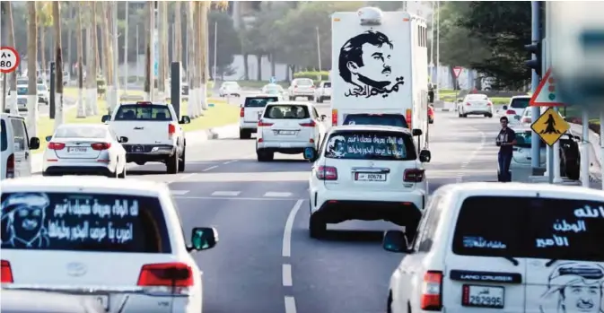  ?? —AFP ?? DOHA: A general view taken on June 11, 2017 shows portraits of Qatar’s Emir Sheikh Tamim bin Hamad Al-Thani on the back of vehicles and text reading in Arabic: “Tamim the glorious”.