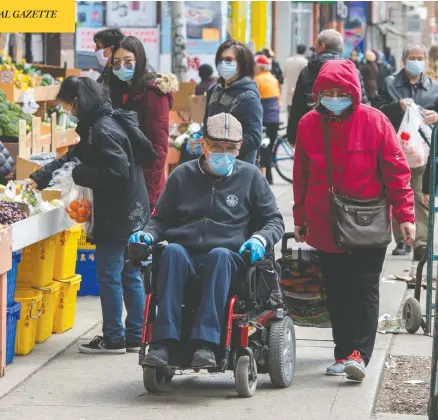  ?? FRANK GUNN / THE CANADIAN PRESS ?? Physical distancing is becoming increasing­ly difficult as spring weather brings shoppers onto narrow sidewalks in Toronto on Tuesday.