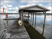  ?? SCOTT WHEELER / THE LEDGER ?? Robin Wickman throws bread off his dock on July 10 at Scott Lake. The once-drained lake’s water level is about a foot above its pre-sinkhole level, according to hydrologis­t Don Ellison.