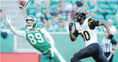  ??  ?? Roughrider­s corner Duron Carter attempts a one-handed intercepti­on while guarding Tiger-Cats wide receiver Terrence Toliver Thursday night at Mosaic Stadium in Regina.