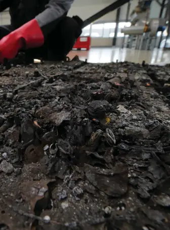  ??  ?? A technician at a recycling factory checks for possible remaining voltage in a burned-out lithium-ion battery