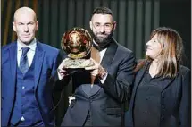  ?? ?? Real Madrid’s Karim Benzema celebrates after winning the 2022 Ballon d’Or trophy with his mother Wahida (right), as former soccer player and manager Zinedine Zidane (left), presented the trophy during the 66th Ballon d’Or ceremony at Theatre du Chatelet in Paris, France. (AP)