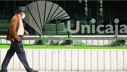  ?? EFE ?? Un hombre pasa ayer frente a la sede central de Unicaja en Málaga