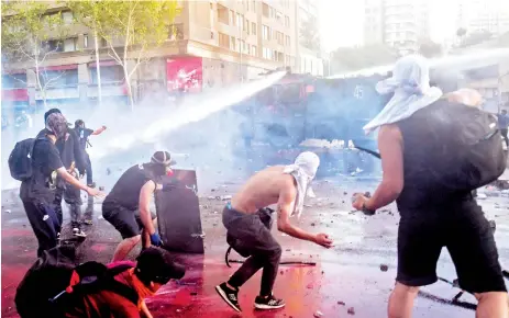  ?? AFP ?? Manifestan­tes chilenos se enfrentan a los carabinero­s durante las protestas del fin de semana en Santiago.