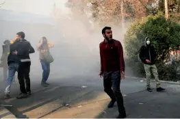  ??  ?? Students attend a protest inside Tehran University while a smoke grenade is thrown by anti- riot Iranian police, in Tehran, Iran, late on Saturday.