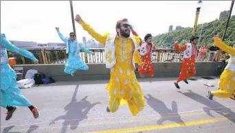  ?? Nate Guidry/Post-Gazette ?? Ian Asenjo, center, and other members of CMU Bhangra, a group composed of Carnegie Mellon University students, perform Sunday on the West End Bridge during Open Streets. Bhangra is a folk dance that originated in Punjab, northern India.